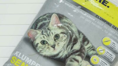 Ein grauer Plastiksack mit Katzenstreu: Piktogramme und oberer Aufdruck sind in grellem Gelb gehalten